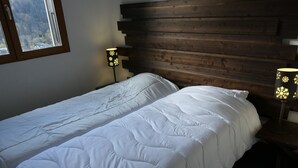 Una habitación con dos camas individuales, cabecera de madera y dos lámparas de noche con diseños de copas de nieve.
