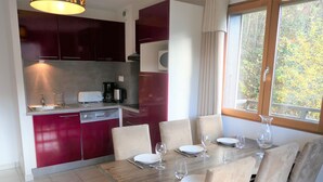 Una cocina moderna con armarios rojo oscuro, un lavamanos de acero inoxidable y una cafetera.