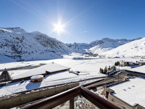 Eine verschneite Berglandschaft mit blauem Himmel, strahlender Sonne und Gebäuden mit schneebedeckten Dächern.