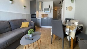 Un espacio habitable compacto con sofá, mesa de comedor y zona de cocina.