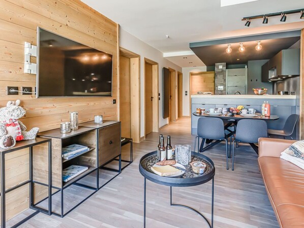 Una sala moderna con un sofá, una mesa de centro, un televisor y un comedor con una mesa y sillas.