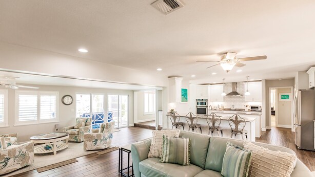 A spacious living room with a green sofa, a round coffee table, and a dining area with a kitchen in the background. - Punta Gorda Isles waterfront pool home (Punta Gorda)