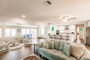 A spacious living room with a green sofa, a round coffee table, and a dining area with a kitchen in the background. - Punta Gorda Isles waterfront pool home (Punta Gorda)