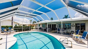 A pool area with a glass roof, lounge chairs, and a view of the surrounding landscape. - Punta Gorda Isles waterfront pool home (Punta Gorda)
