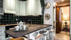 Une cuisine moderne avec des meubles blancs, un plan de travail foncé et un îlot central doté de tabourets de bar.