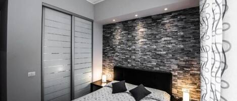 A bedroom with a bed, a nightstand, a wall-mounted TV, and a wardrobe.