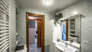 Une salle de bain avec un lavabo blanc, un miroir et des murs carrelés.