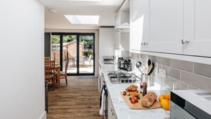 Une cuisine moderne dotée d’une lucarne, un coin repas avec des chaises en bois et une vue sur le jardin.