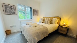 A bedroom with a bed, bedside tables, a lamp, and artwork on the walls. - Spacious One Bed Apt With Scenic Views (Ventnor)