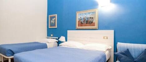 Habitación de hotel con dos camas, una pared azul y un cuadro.