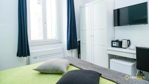 A hotel room with a bed, a desk, a TV, and a window with curtains. - Lia Rooms (La Spezia)