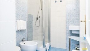 A bathroom with a glass-enclosed shower, a white sink, and a toilet. - Lia Rooms (La Spezia)