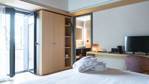 A hotel room with a bed, a desk with a TV, a wardrobe, and a bathroom visible through an open door. - Bahal dell Etna (Ramacca)