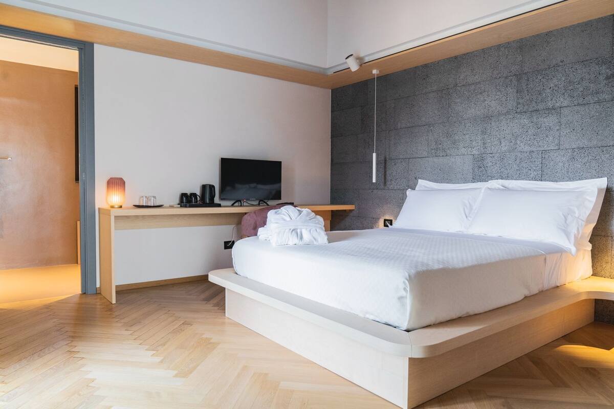 A modern bedroom with a bed, bedside table, and a desk with a television.