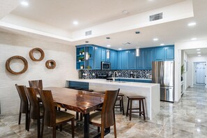 Enjoy meals in the kitchen with a central island, stainless steel appliances, and a dining area with a wooden table.
