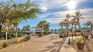 A resort pathway lined with palm trees and thatched umbrellas, leading to a pool area. - Brand New and Spacious 4 Bedroom CondoC-30202 (Puerto Peñasco)