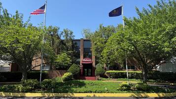 A building with a red awning labeled "Chevrolet" and two flags, one American and one state flag, flying on flagpoles.