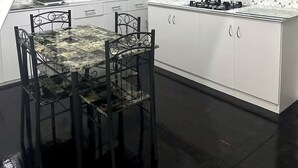 Uma cozinha moderna com armários brancos, painel de azulejos preta e branca, e uma ilha central com fogão a gás.