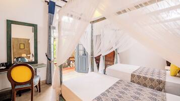 A bedroom with two beds, a desk, and a chair.