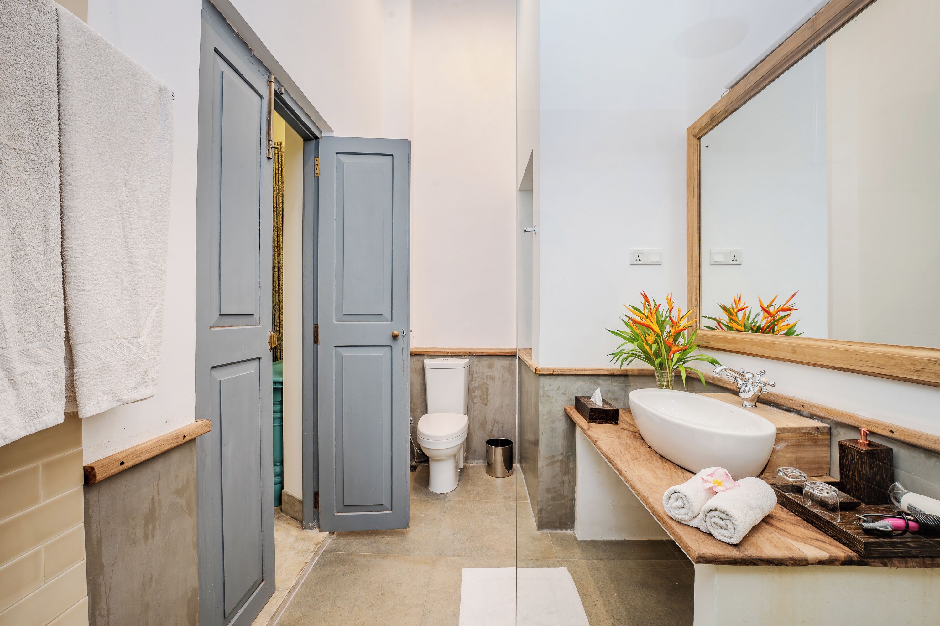 A bathroom with a wooden vanity, a large mirror, a toilet, and a towel rack.