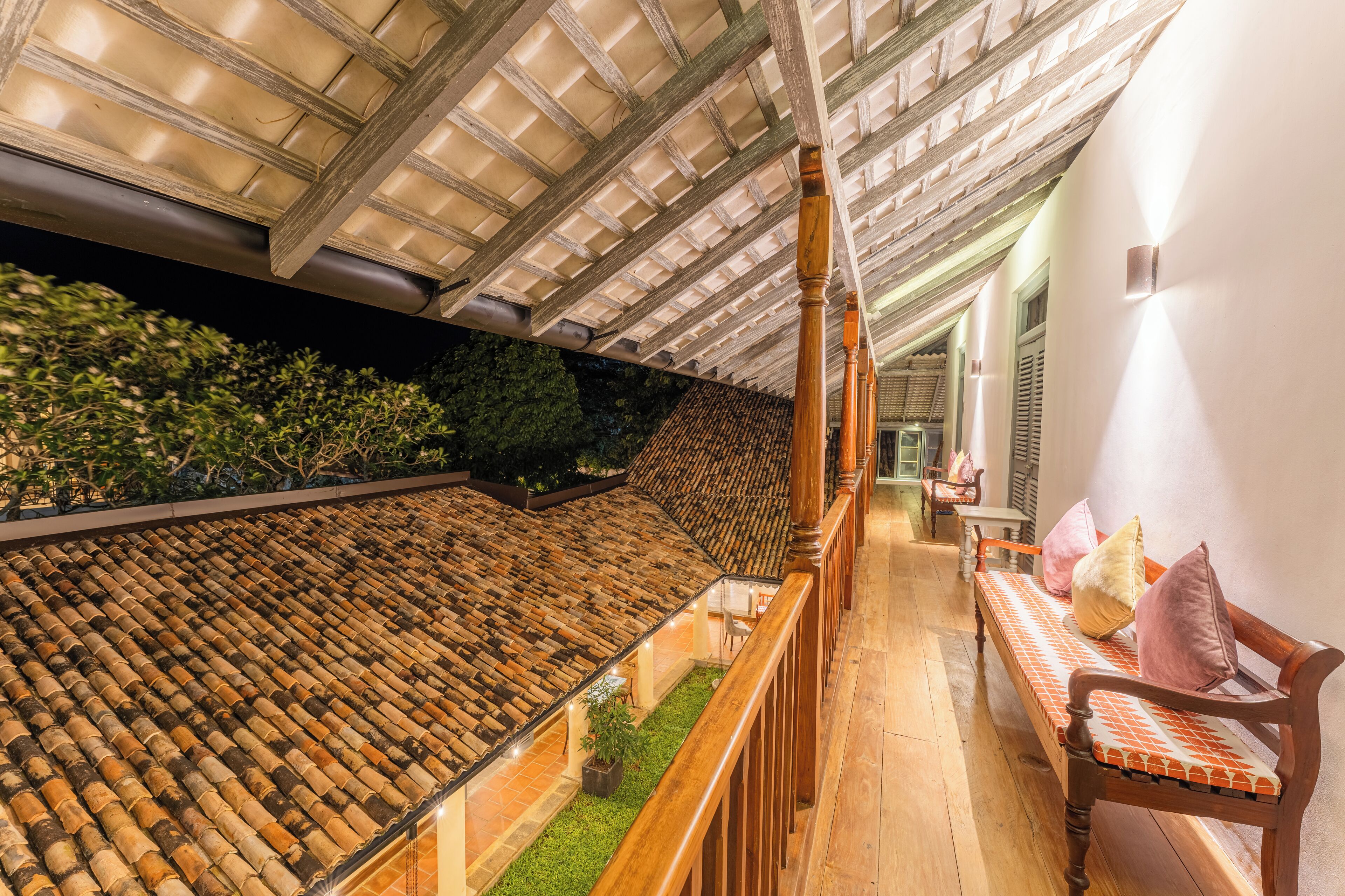 A rooftop terrace with a wooden bench, a glass balustrade, and a tiled roof.