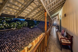 A covered outdoor area with a tiled roof, wooden railing, and a bench.