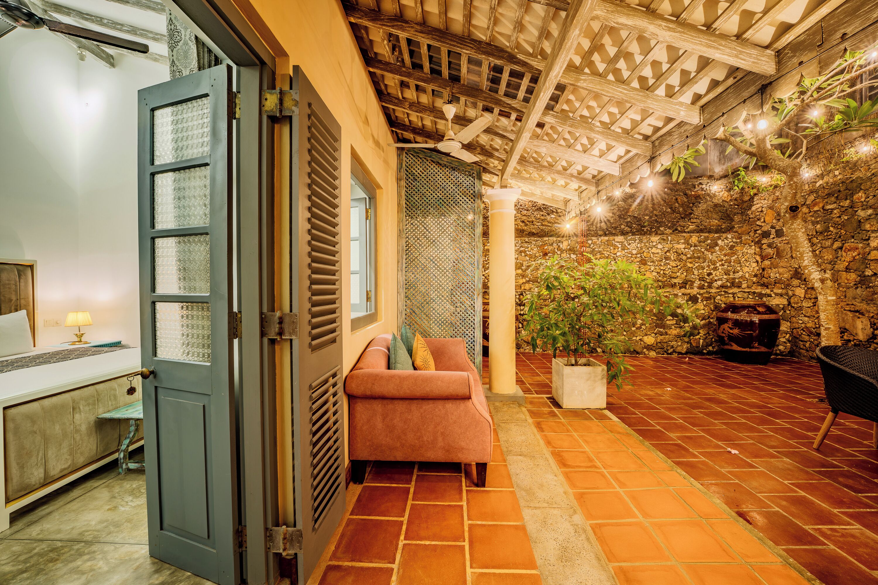 A cozy interior with a wooden ceiling, a stone wall, and a potted plant.