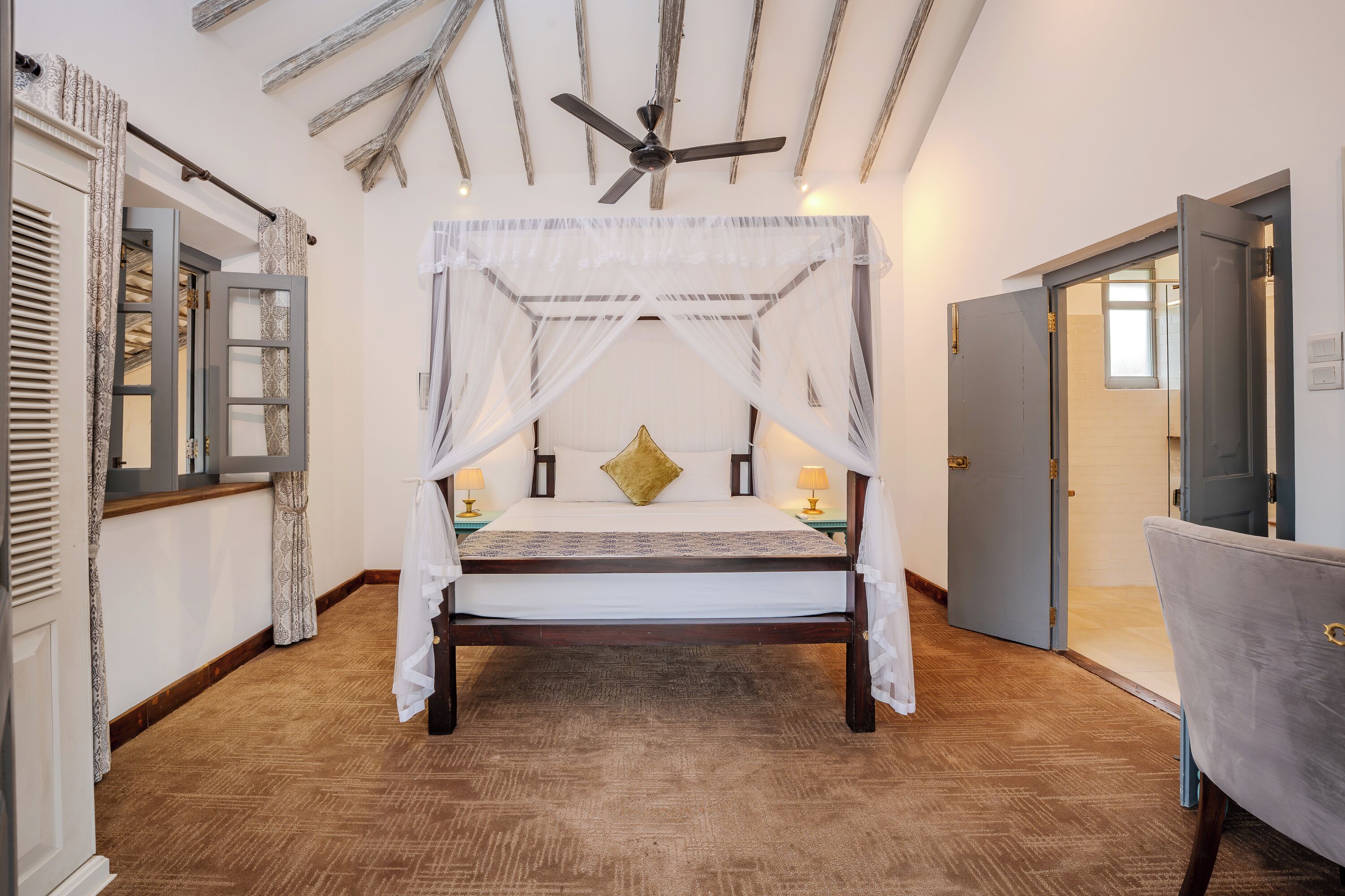 Un dormitorio con cama con dosel, ventilador de techo y suelo de madera.