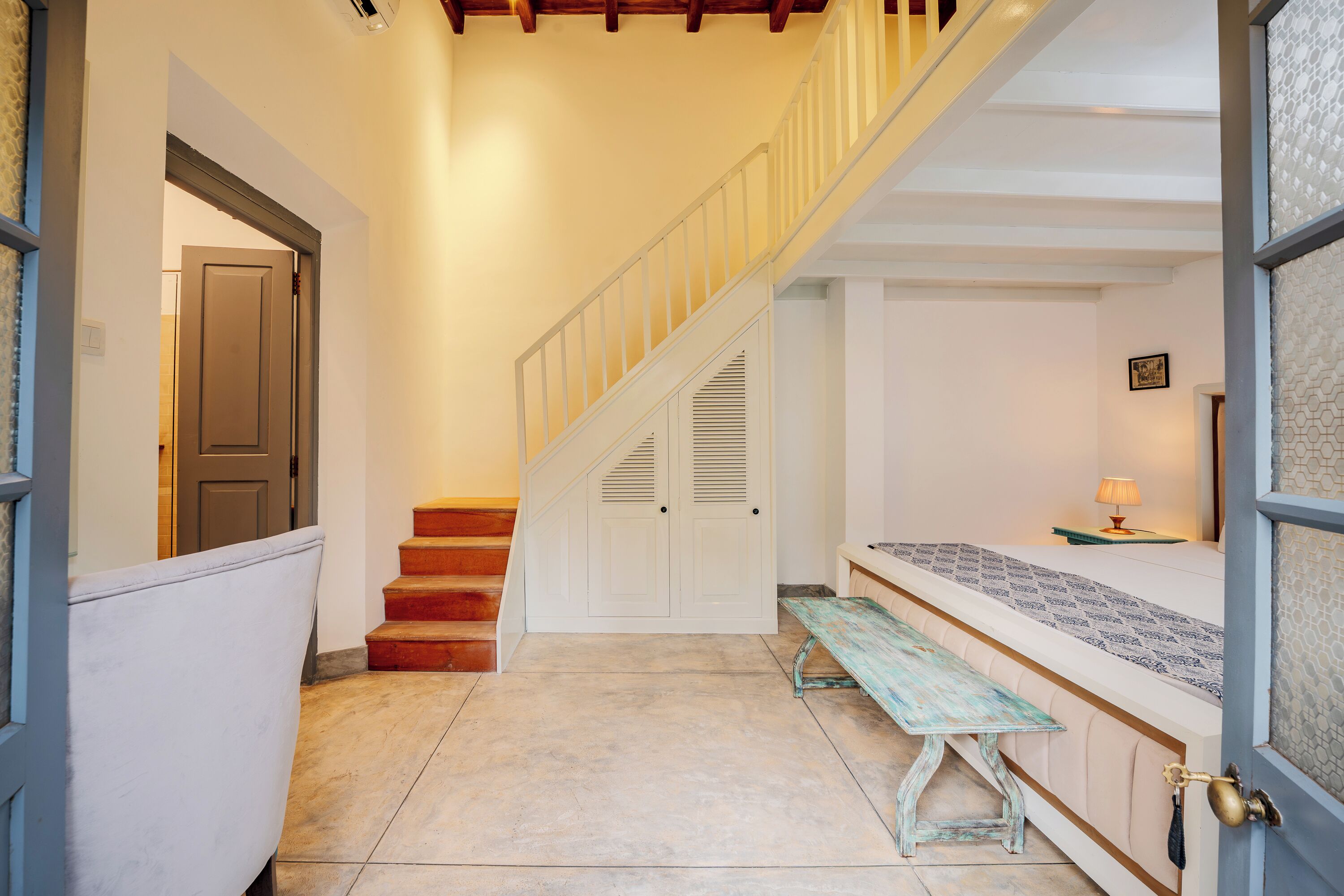 Un escalier avec des rampes blanches, un banc et une nappe à motifs.