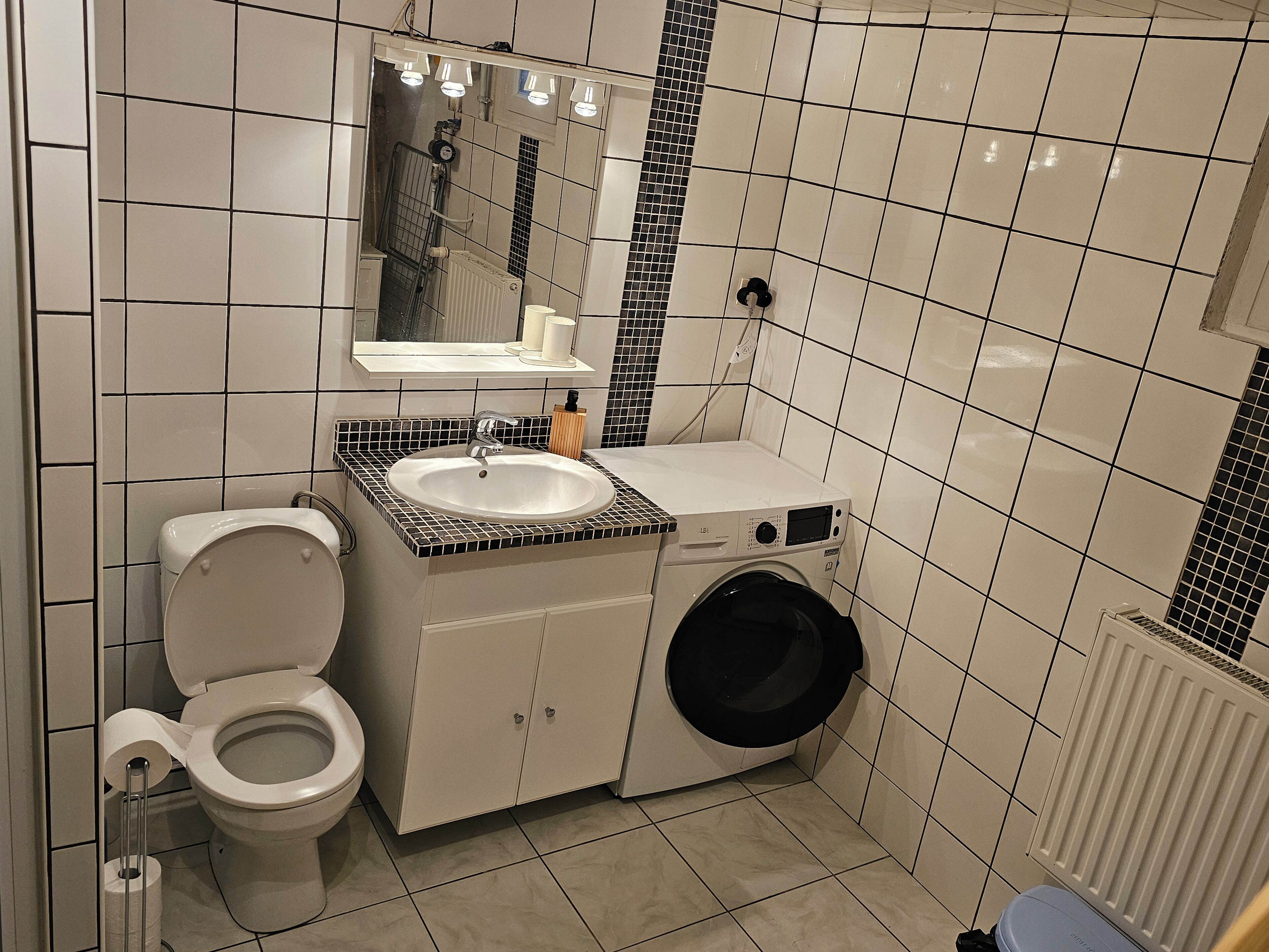A compact bathroom with a toilet, sink, and washing machine.