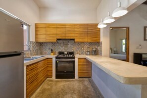 Enjoy cooking in this well-equipped kitchen with a large island, refrigerator, stove, oven, sink, and coffee maker.