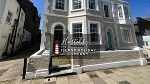 Un edificio de dos pisos con fachada blanca, múltiples ventanas y un letrero que indica que es administrado por Island Holiday Company.