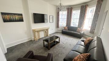 A living room with a fireplace, a sofa, a coffee table, and a TV.