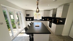 Una cocina moderna con una isla central, armarios blancos y un amplio ventanal que proporciona luz natural.