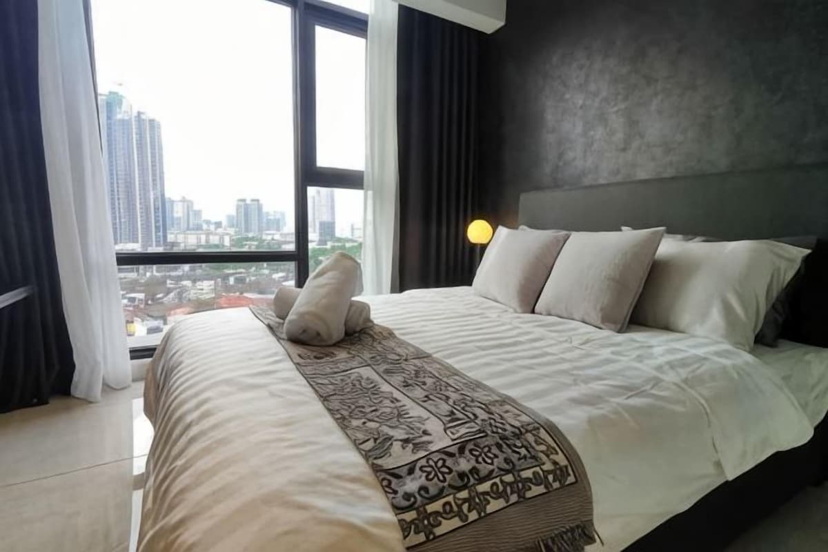 Una habitación de hotel con una cama grande, vistas a la ciudad y un diseño moderno.