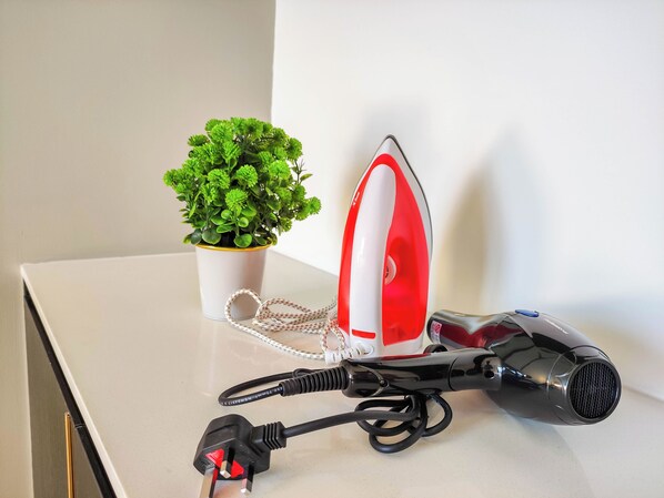 A table with an iron, a hairdryer, and a potted plant. - The AXON @ Bukit Bintang (Kuala Lumpur)