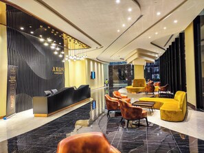 Un moderno vestíbulo de hotel con mostrador de recepción, zona de estar y un espejo grande.