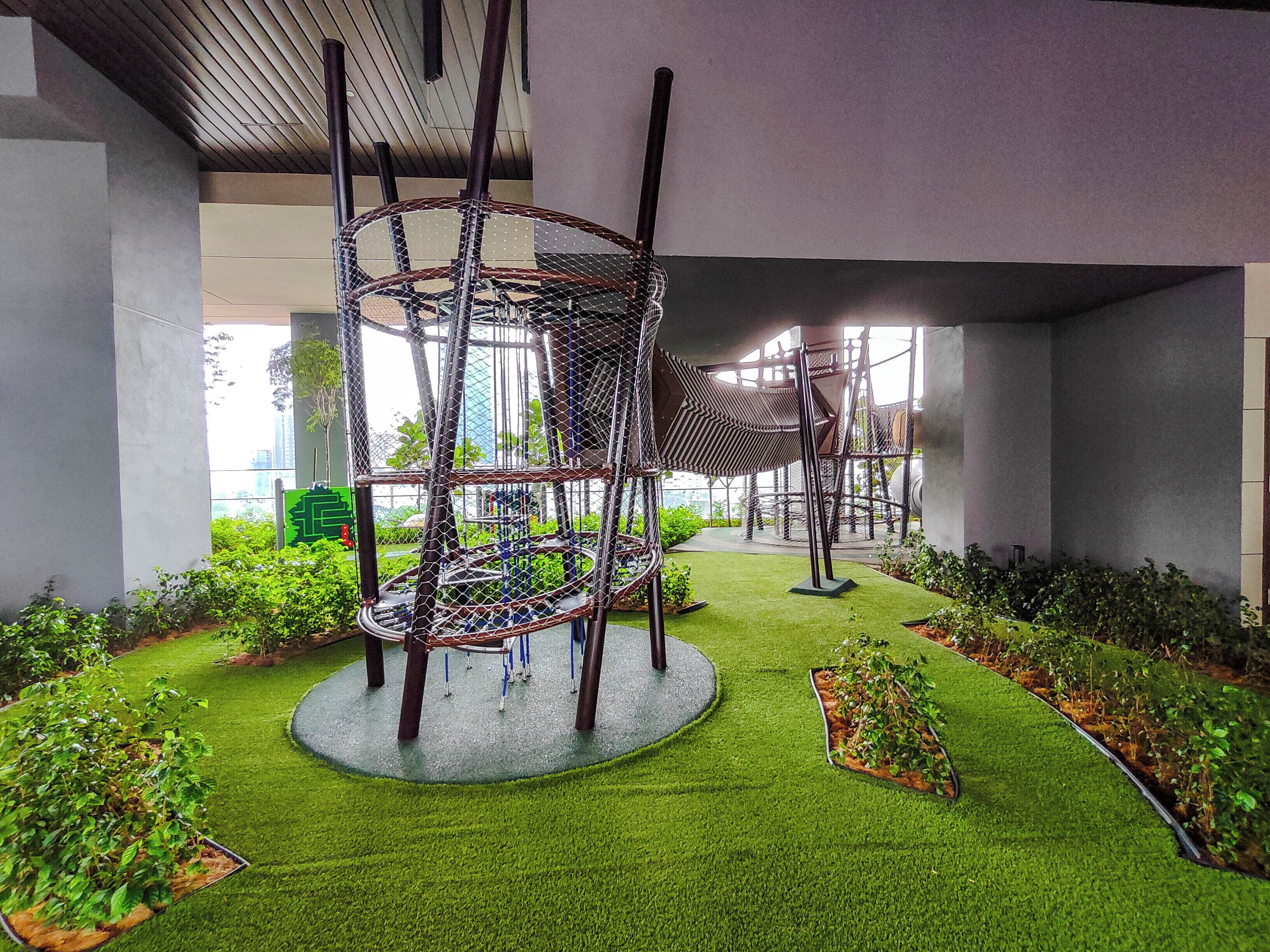 Un jardin intérieur moderne, avec une sculpture métallique au centre, entourée de gazon synthétique et de plantes en pot.