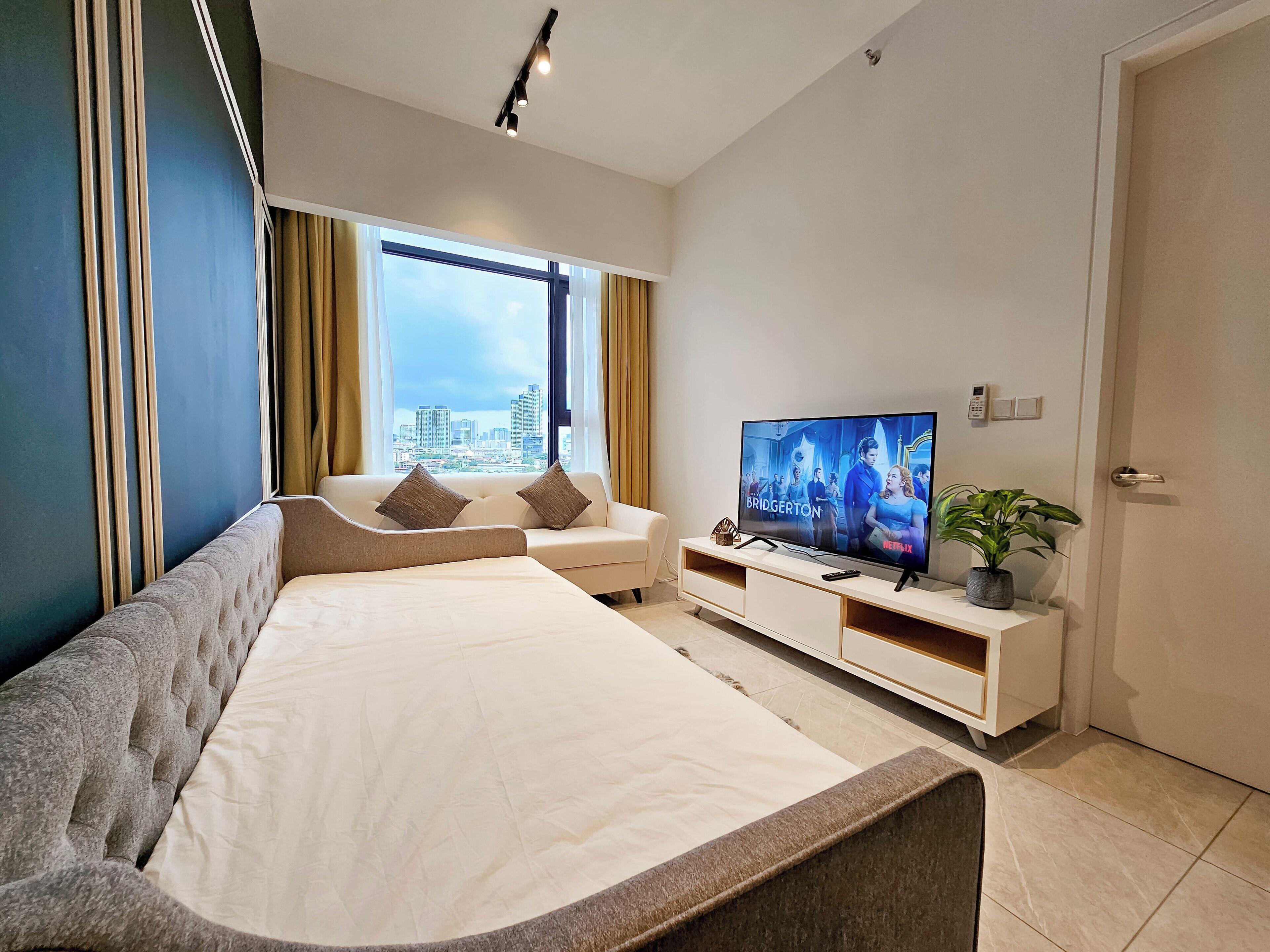 A modern hotel room with a large bed, a TV, and a city view.