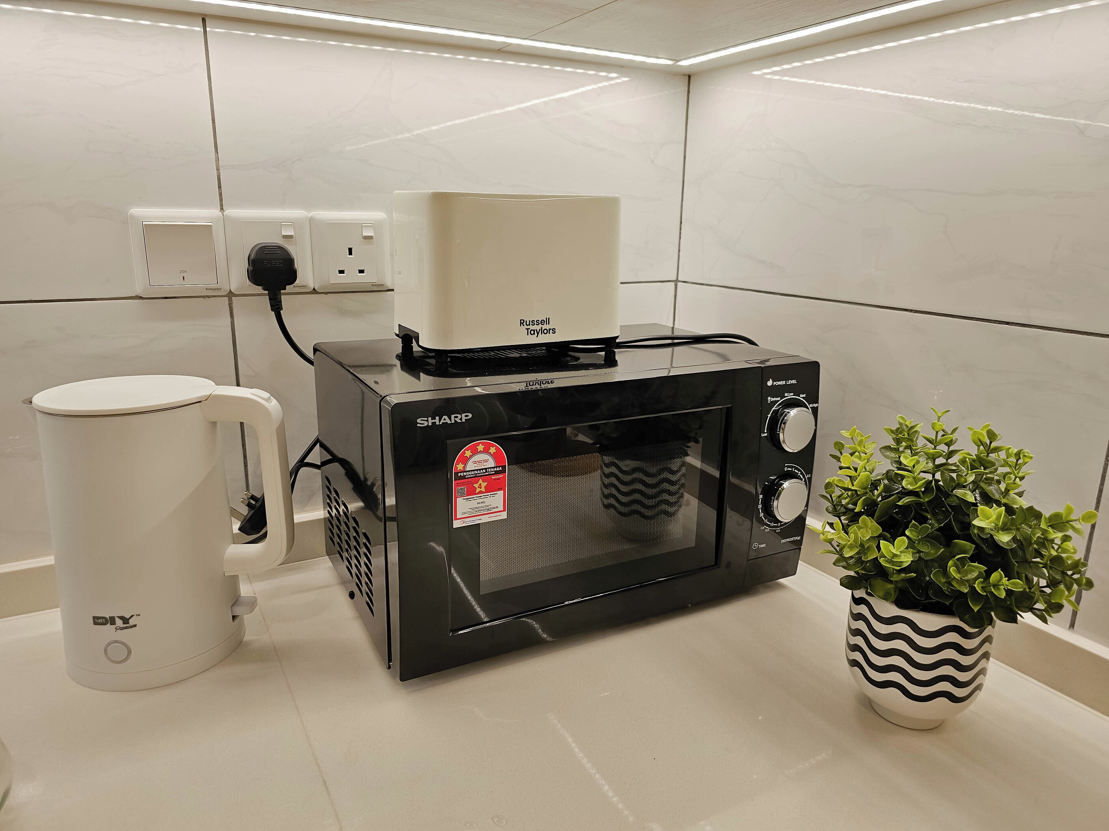 A kitchen with a microwave, a coffee maker, and a potted plant.