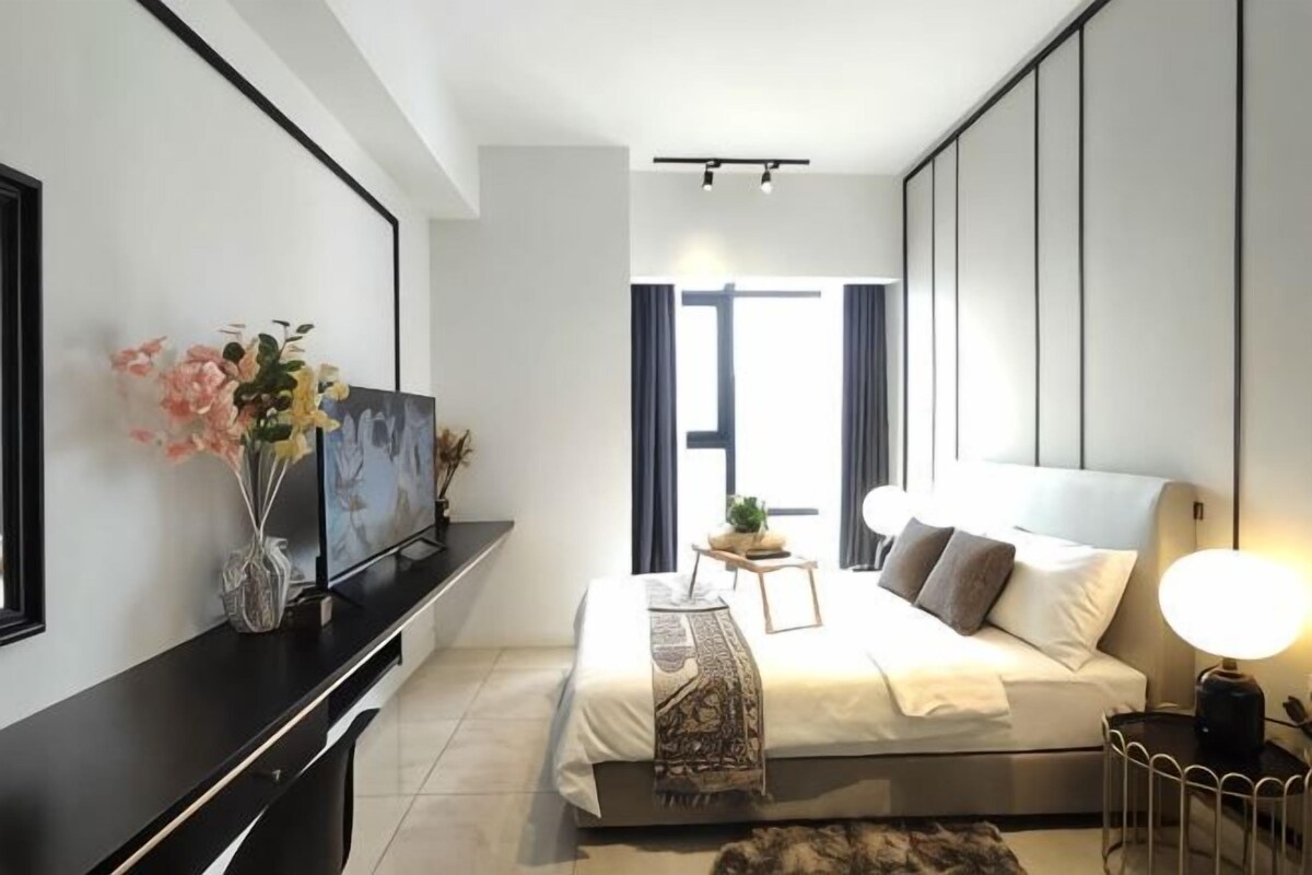 A modern bedroom with a bed, bedside table, TV, and artwork.