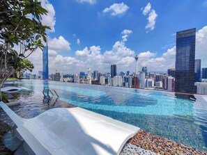Una piscina infinita en la azotea con un horizonte urbano de fondo.
