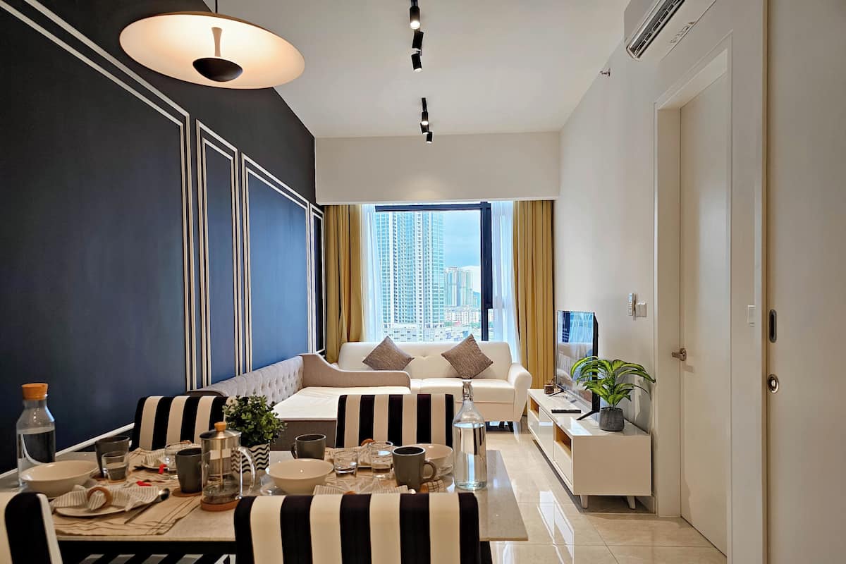 Una sala moderna con sofá, mesa de comedor y un amplio ventanal con vistas a la ciudad.