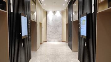 A modern elevator lobby with a marble floor and vertical black panels on the walls.