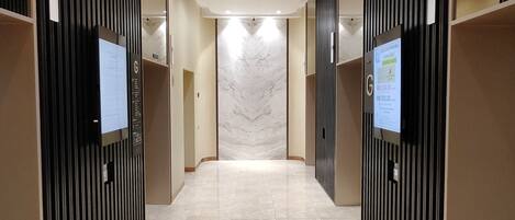 A modern elevator lobby with a marble floor and vertical black panels on the walls.