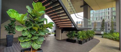A modern building with a wooden staircase, potted plants, and a wooden deck.