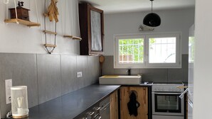 Une cuisine dotée d’une cuisinière moderne, de meubles en bois et d’une fenêtre laissant entrer la lumière naturelle.