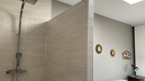 Une salle de bain moderne avec une douche, un lit et une table de chevet avec une lampe.