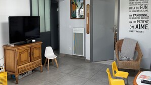 Un salon moderne doté d’un téléviseur à écran plat, d’un meuble en bois et d’un luminaire au plafond.
