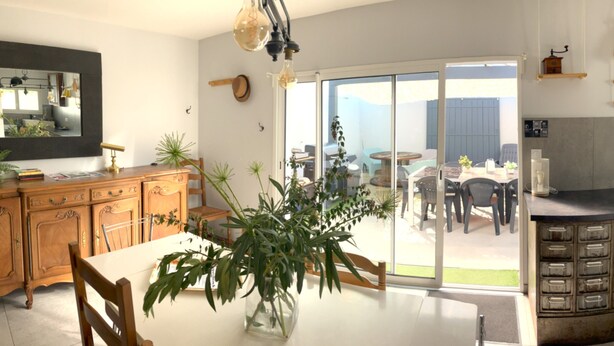 Une cuisine moderne avec un coin repas, des portes-fenêtres coulissantes donnant sur une terrasse et un lave-vaisselle encastré.